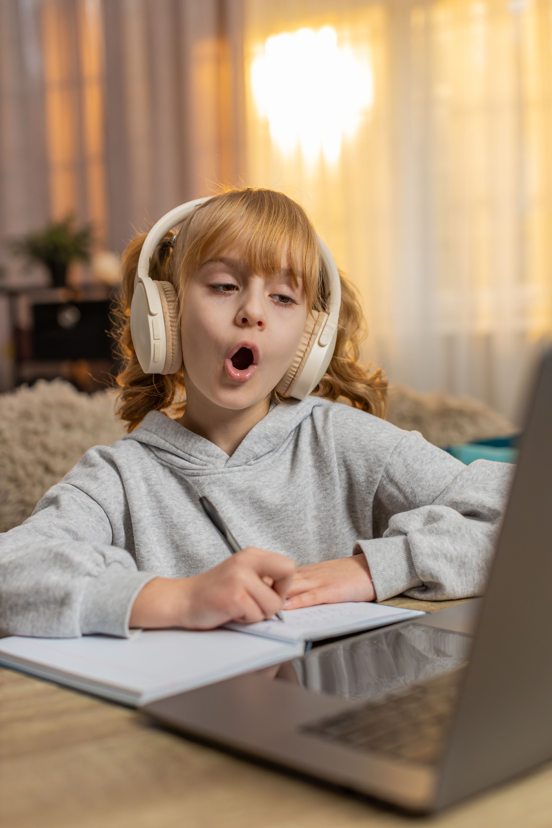 Young girl wearing wireless headphones learning English with audio lesson repeating new words aloud