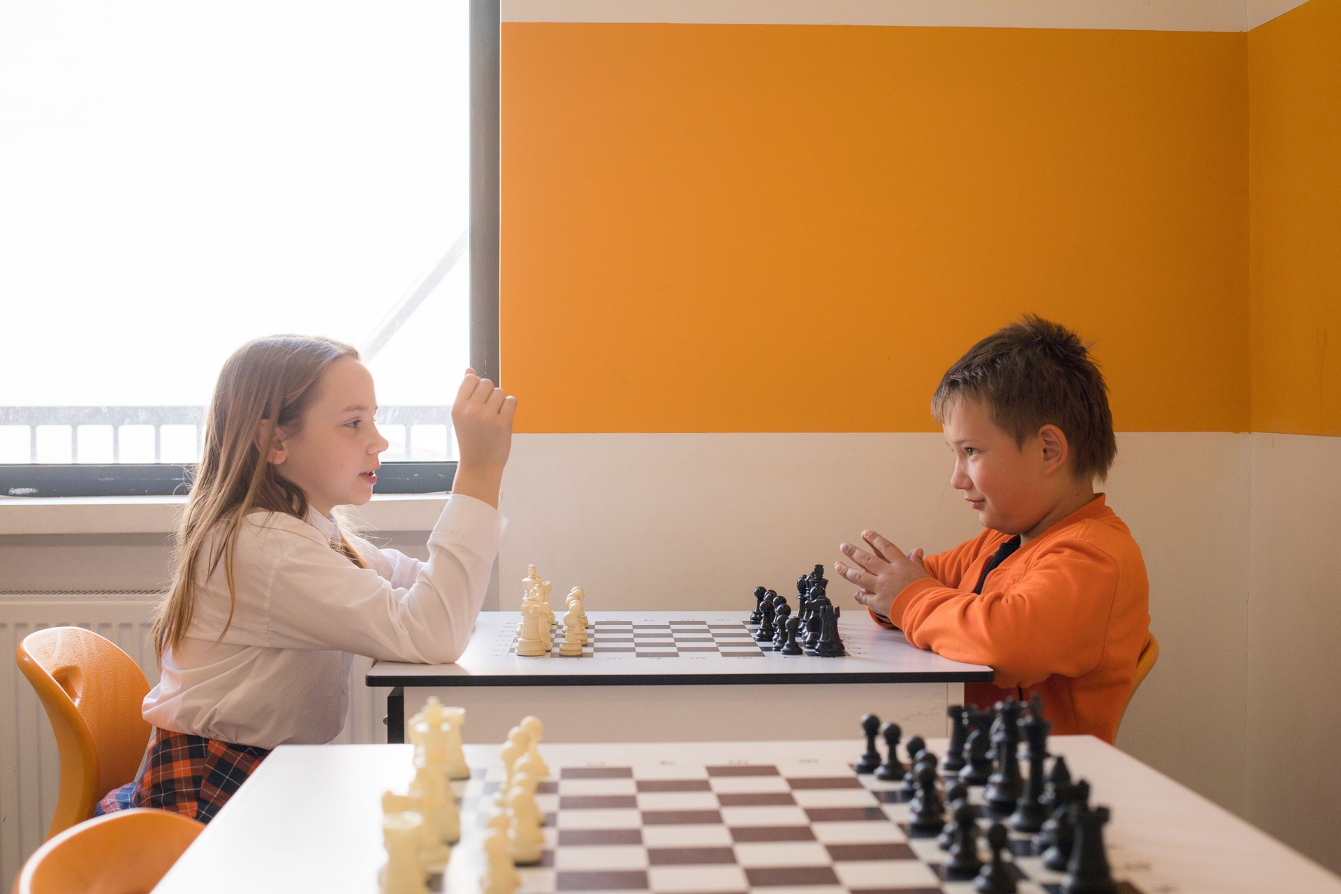 Cheerful children school student playing chess in classroom at school