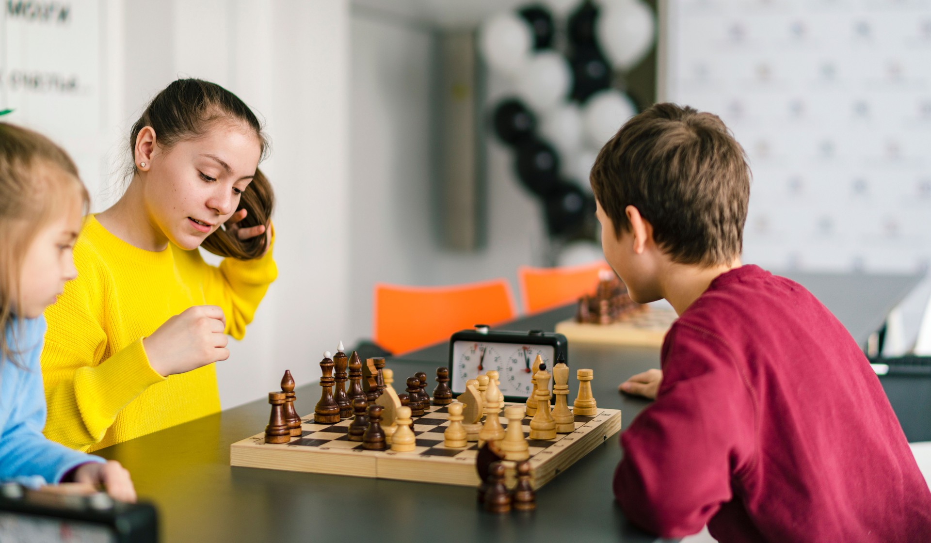 Kids of different ages, boys and girls, playing chess on the tournament in the chess club