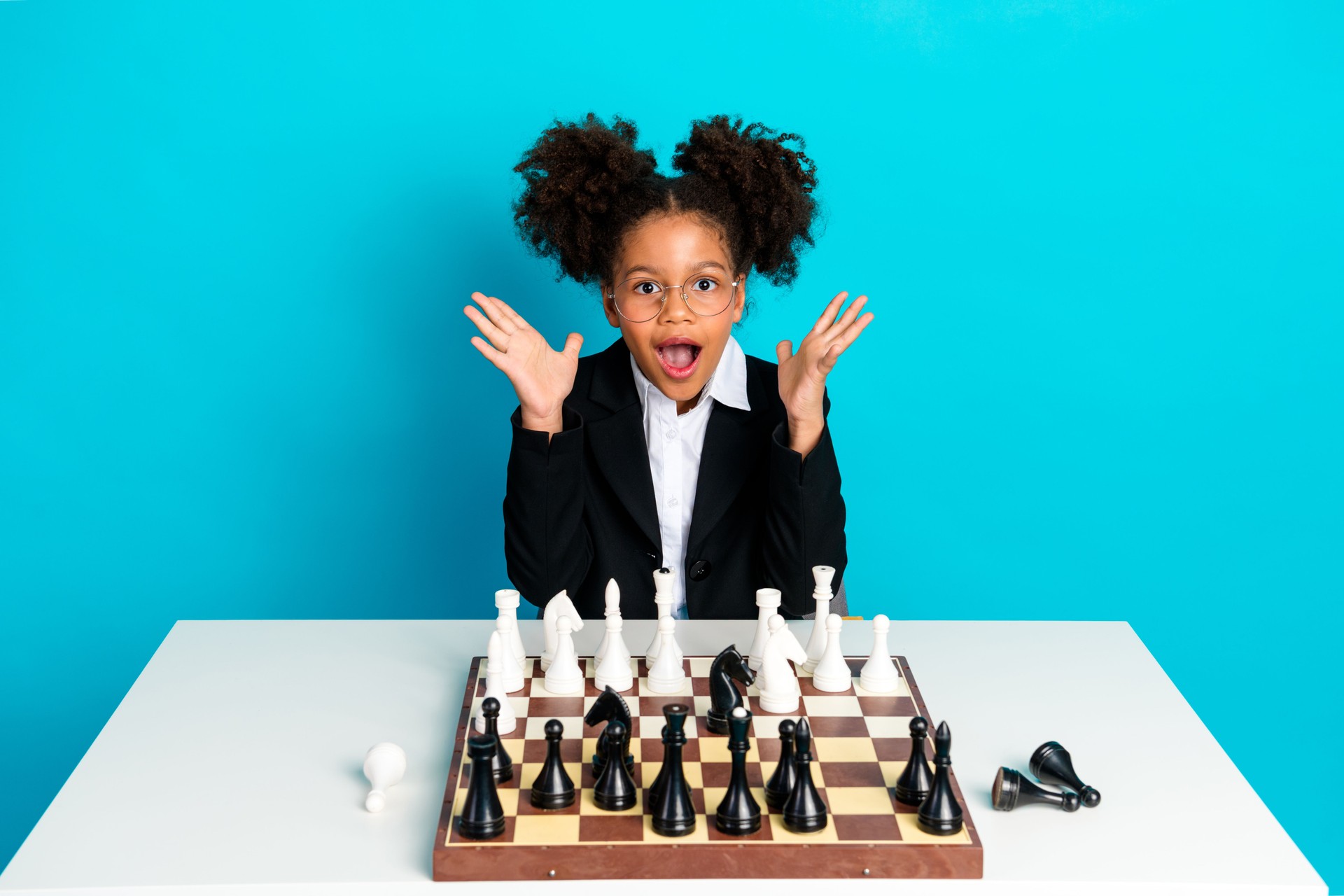 Happy schoolgirl excitedly gesturing at chessboard while studying in colorful setting, symbolizing young intelligence and enthusiasm